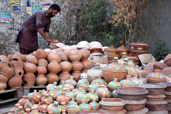 A vendor arranging and displaying the different kinds of clay pots to attract the customers at roadside setup