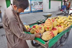 A vendor paints fruit Cantaloupes to the attention of the customers that makes increase his sell.
