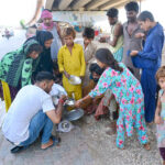 Volunteers distributing free food to nomadic people in Qasimabad