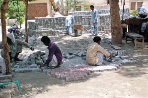 Laborers busy in tuff tiles work along the road.