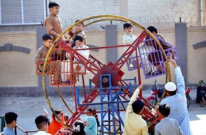 Children enjoying a portable swing at the roadside in the Tehsil area.