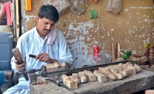 A skilled worker carving design on wood at his workplace.
