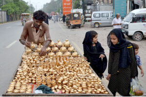 Children buy golden clay pots and money-boxes from a hawker's handcart at near Bibi Pak Daman.