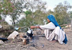 Flood affected woman making tea outside her temporary shelter at Larkana-Tando Masti Road.