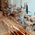 A carpenter crafting wooden stair railings as part of his daily routine at his workshop