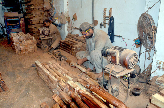 A carpenter crafting wooden stair railings as part of his daily routine at his workshop