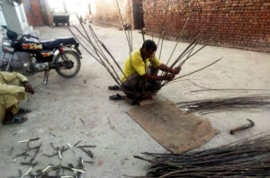 A wooden basket maker in the provincial capital works diligently at his workplace, showcasing his skilled craftsmanship.