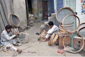 Worker busy in making a large strainer for customers at a roadside setup in the city.