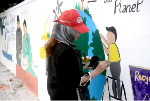 Art students from various colleges and universities painting a mural on the Radio Pakistan building to attract passersby and students.