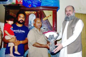 Federal Minister for Commerce Jam Kamal Khan presenting a bouquet to the family of Martyred Soldier Haroon William in tribute during a Defence Day visit to their home.