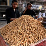 Vendor arranging and displaying traditional sweets item at roadside in the Federal Capital