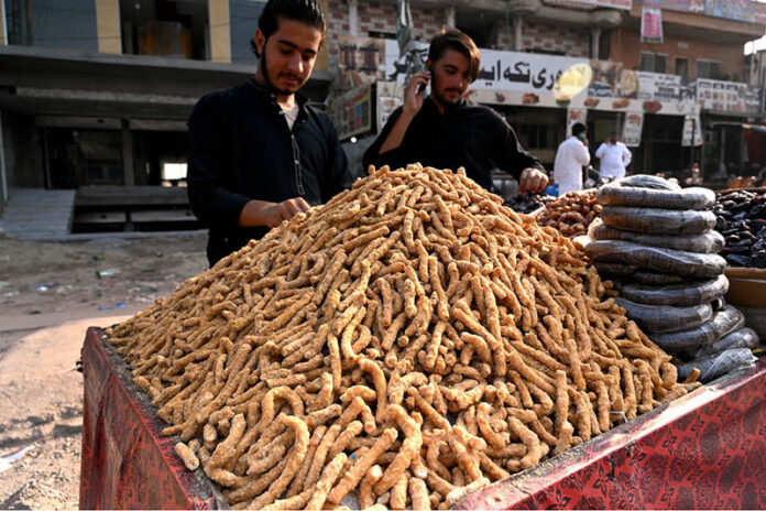 Vendor arranging and displaying traditional sweets item at roadside in the Federal Capital