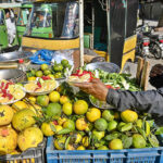 A vendor slices and arranges fresh citrus fruits onto plates outside Benazir Hospital, creating a fresh and colorful display to catch the eye of passing customer