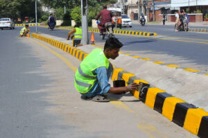 PHA staffers busy painting the road divider near Pul Moj Darya as part of the city's beautification efforts