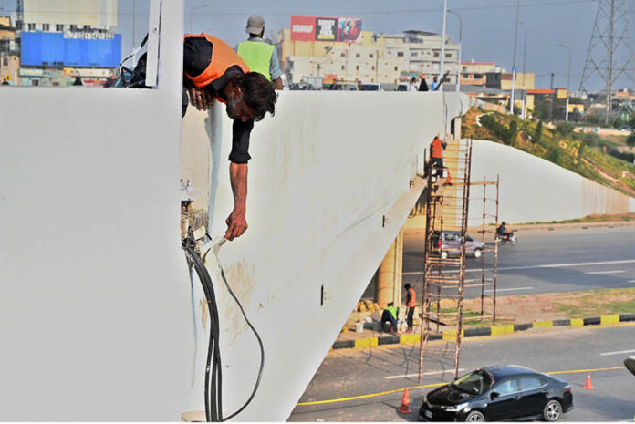 Laborers hard at work painting a flyover bridge, adding a fresh touch to the Federal Capital infrastructure