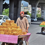 Street vendors push their handcarts with sweets items on the busy Murree Road, seeking customers amidst the lively crowd