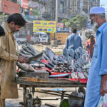 Customers gather, inspecting fresh fish for buying at a vendor’s stall at Khanna Pul in twin cities