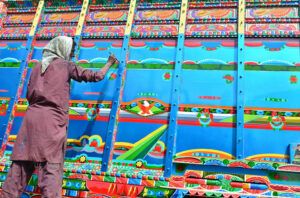 A painter is busy painting the body of a truck at his workplace.