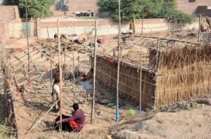 A nomadic family is busy building their makeshift home on the outskirts of the city.