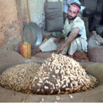 A man roasts fresh peanuts at his shop, a popular winter treat in high demand for its seasonal warmth and rich flavor