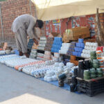 A vendor is busy arranging and displaying Teacups to attract customers at his roadside setup