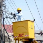 A worker fixing electric cables on a pole
