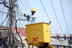 A worker fixing electric cables on a pole