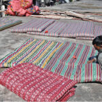 A worker busy in stitching a quilt at his workshop in preparation for the upcoming winter season