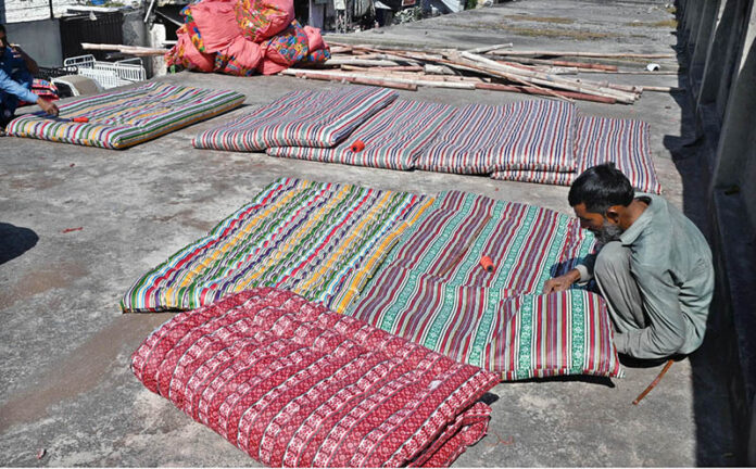 A worker busy in stitching a quilt at his workshop in preparation for the upcoming winter season