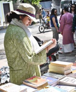 A woman busy in selecting and purchasing old books from roadside stall at Mall Road