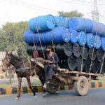A Donkey cart holder on the way while loaded with empty drums to deliver in the market