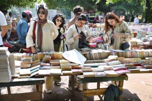 A woman busy in selecting and purchasing old books from roadside stall at Mall Road