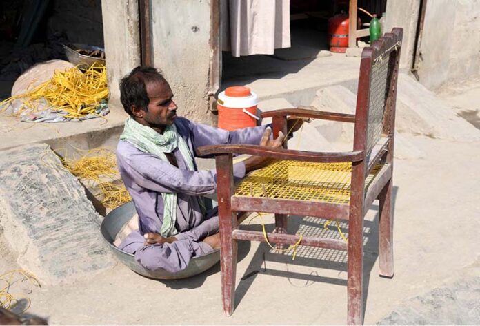 A disabled person is busy repairing a chair in front of his shop near Bakapur Village