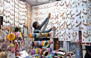 A vendor displays beautiful artificial jewelry at Resham Gali, drawing customers as high gold prices and the wedding season boost demand in the city.