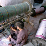 Workers busy in preparing and arranging thread for preparing fabric by machine at a local textile factory