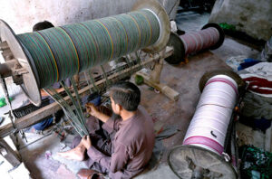 Workers busy in preparing and arranging thread for preparing fabric by machine at a local textile factory