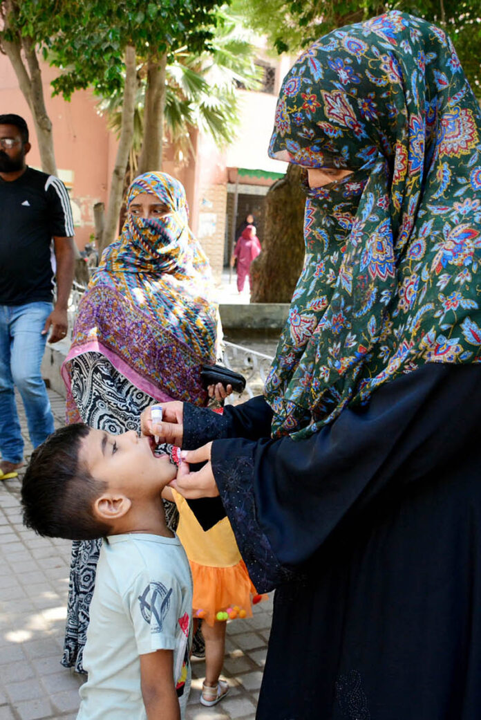 A female health worker administers polio drops to children during a vaccination drive aimed at eradicating polio in Pakistan