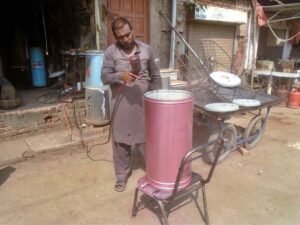 A painter busy in painting a geyser at his workplace as demand increased during winter season