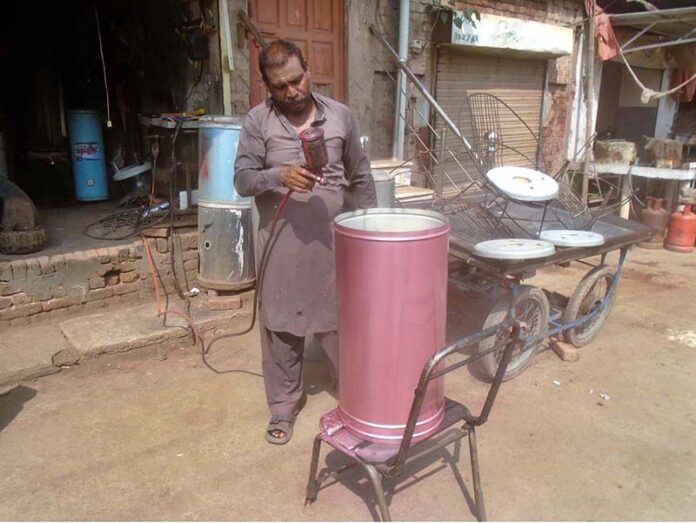 A painter busy in painting a geyser at his workplace as demand increased during winter season