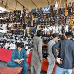 People selecting and purchasing shoes from setup under the shade of Makki Shah Flyover