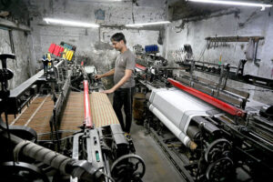 Workers busy in preparing and arranging thread for preparing fabric by machine at a local textile factory