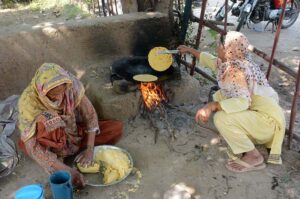 A woman prepares traditional corn bread served with mustard curry at her stall during the Rabi Gur Mela at the University of Agriculture, Faisalabad (UAF).