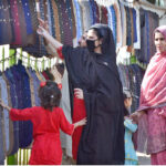 A family is busy selecting and purchasing waistcoats from the roadside vendor