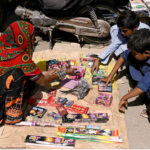 Woman vendor displaying the firework stuff to attract the customers in connection with upcoming Hindu festival Dewali at Market Road