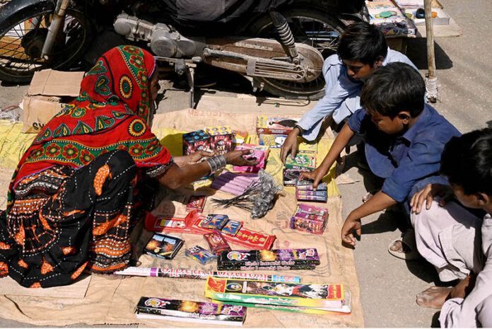 Woman vendor displaying the firework stuff to attract the customers in connection with upcoming Hindu festival Dewali at Market Road