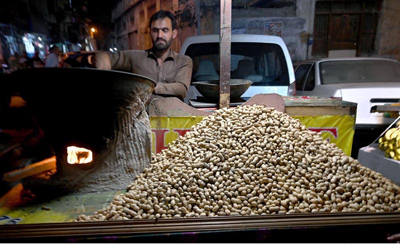 A hawker roasts fresh peanuts at his stall, a popular winter treat in high demand for its seasonal warmth and rich flavor
