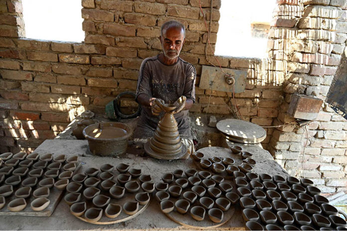 An artisan busy preparing traditional clay-made oil lamp for use upcoming Hindu festival Dewali at his workplace in kumharpara