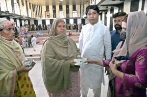 Deputy Director, BISP Raazia Yasmeen giving cash to deserving women at Benazir Income Support Program Quarterly Payment Distribution Center established at Company Bagh.
