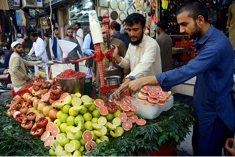 A vendor extracting pomegranate and grapefruit juices for customers at Qissa Khawani Bazaar
