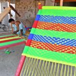 A worker busy in knitting traditional bed (charpai) at his workplace